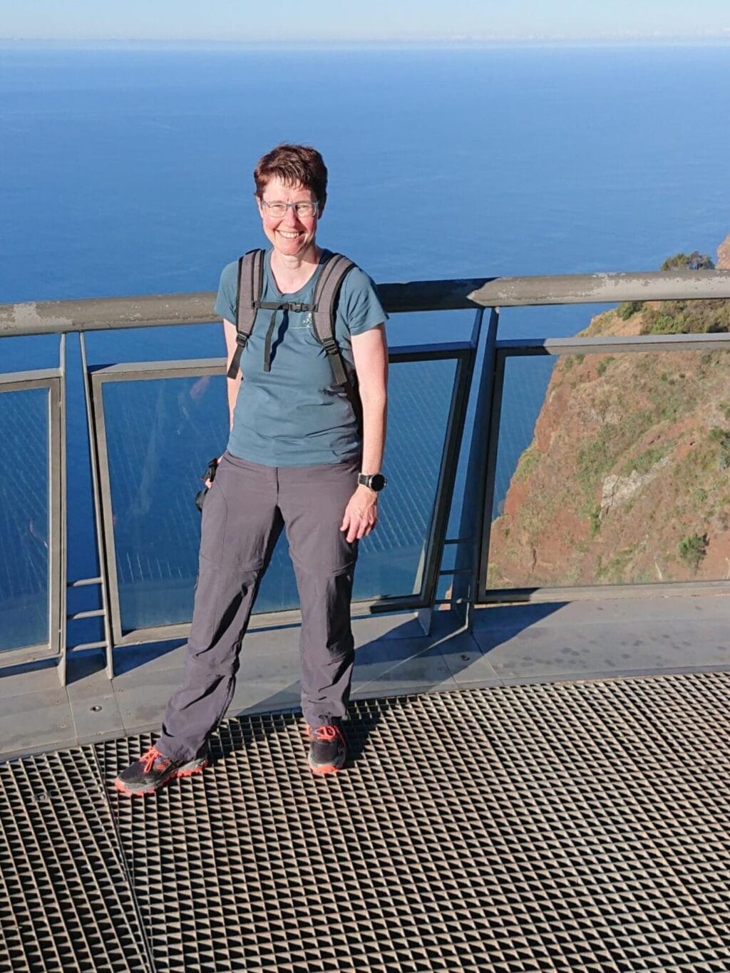 Eine Frau steht auf einer Aussichtsplattform. Im Hintergrund ist das Meer zu sehen.